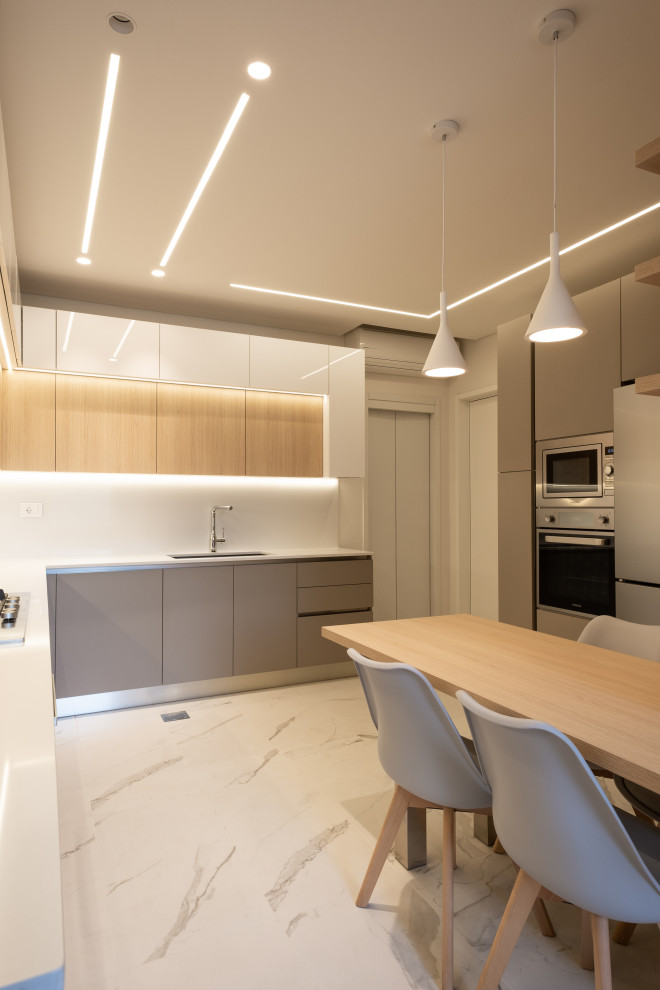 На фото: большая угловая кухня: освещение в стиле модернизм с мраморным полом и многоуровневым потолком с