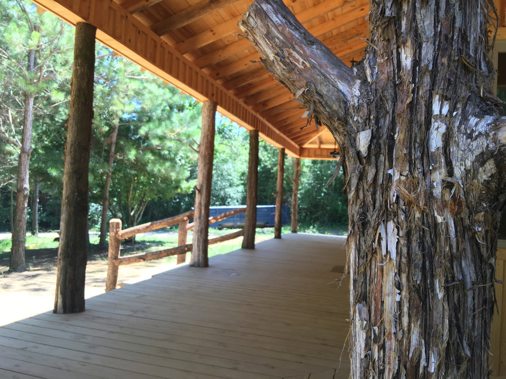 This is an example of a large rustic front porch design with decking and a roof extension.