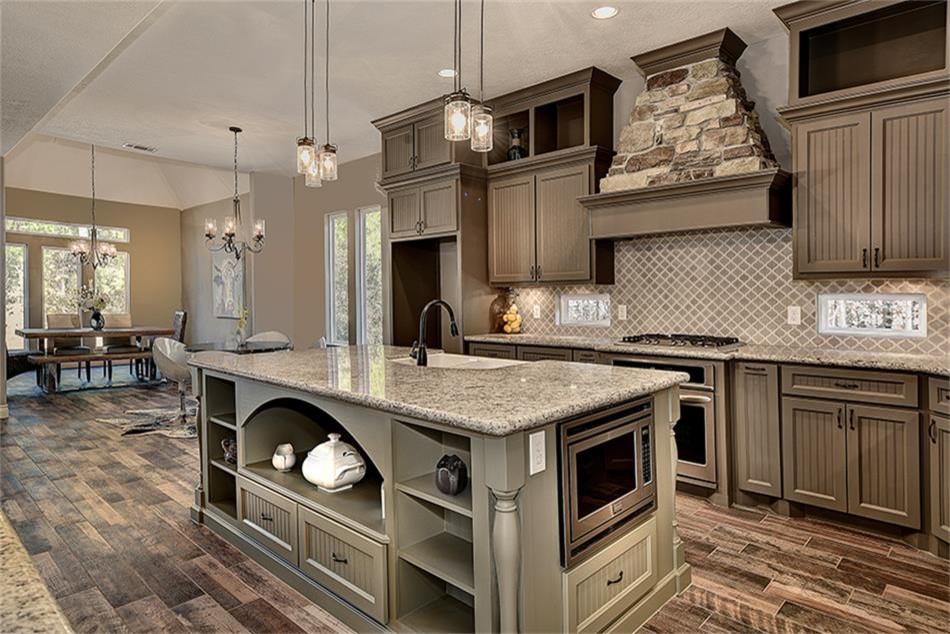 Design ideas for a mid-sized transitional u-shaped open plan kitchen in Houston with a farmhouse sink, shaker cabinets, brown cabinets, granite benchtops, beige splashback, ceramic splashback, stainless steel appliances, porcelain floors, with island, brown floor and blue benchtop.