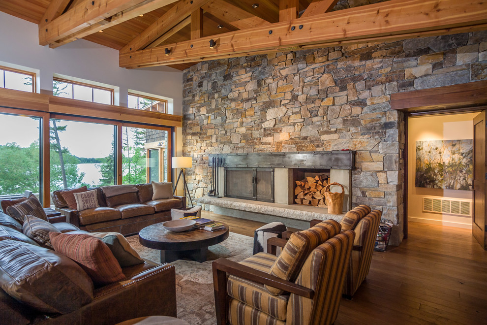 Photo of a country open concept living room in Seattle with beige walls, medium hardwood floors, a wood stove and a stone fireplace surround.