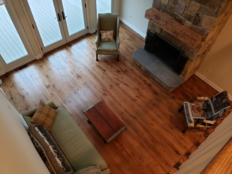 Ejemplo de sala de estar abierta y abovedada de estilo de casa de campo grande con suelo de madera en tonos medios, todas las chimeneas, marco de chimenea de piedra y suelo marrón
