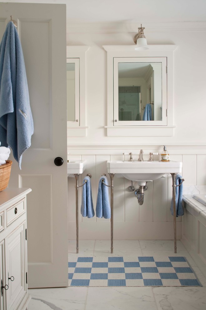 Inspiration for a mid-sized traditional master bathroom in Boston with a console sink, a drop-in tub, a two-piece toilet, white tile, white walls and marble floors.