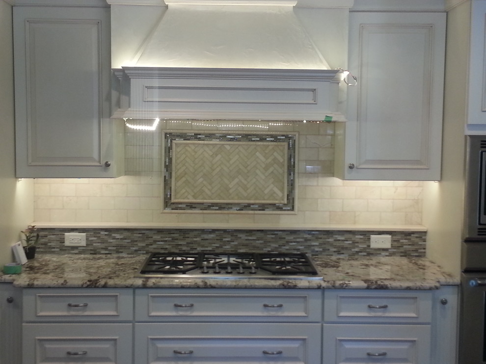 Inspiration for a mid-sized l-shaped light wood floor eat-in kitchen remodel in Newark with a drop-in sink, raised-panel cabinets, white cabinets, granite countertops, white backsplash, subway tile backsplash, stainless steel appliances and an island
