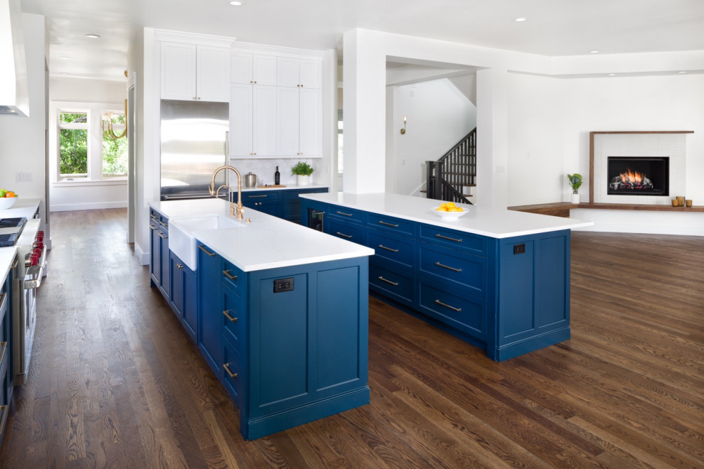 This is an example of a beach style l-shaped open plan kitchen in Denver with flat-panel cabinets, quartzite benchtops, medium hardwood floors and multiple islands.