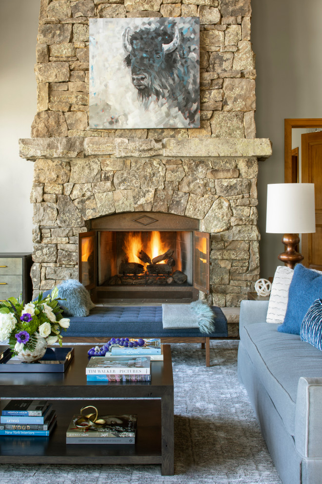 This is an example of a large country open concept living room in Denver with grey walls, medium hardwood floors, a standard fireplace, a stone fireplace surround, brown floor and exposed beam.