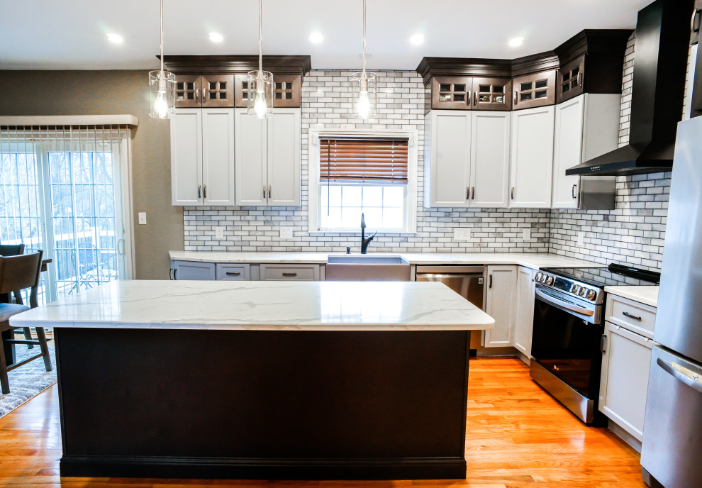 Photo of a transitional kitchen in Philadelphia with raised-panel cabinets, grey cabinets, quartz benchtops, mosaic tile splashback, light hardwood floors, with island, orange floor and white benchtop.