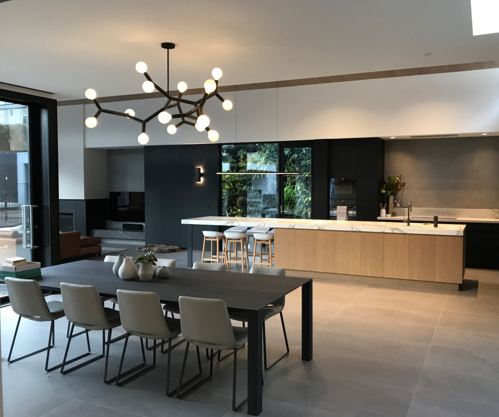 Design ideas for an expansive contemporary galley eat-in kitchen in Melbourne with an undermount sink, flat-panel cabinets, black cabinets, grey splashback, panelled appliances, porcelain floors, with island, grey floor and white benchtop.