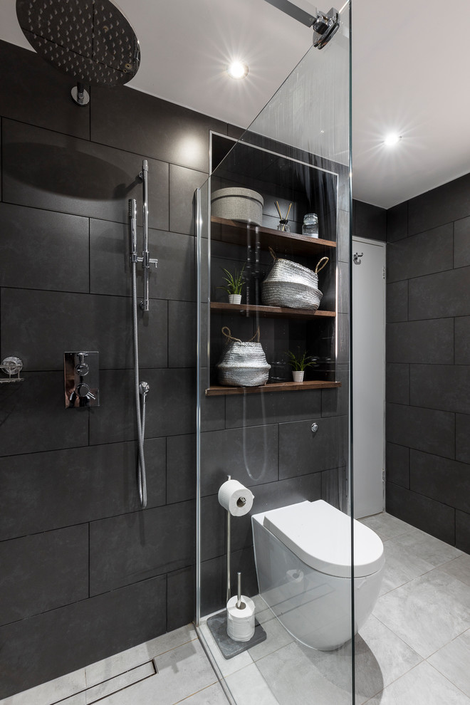 Photo of a large modern kids bathroom in London with raised-panel cabinets, dark wood cabinets, a freestanding tub, a shower/bathtub combo, a one-piece toilet, gray tile, cement tile, grey walls, ceramic floors, a pedestal sink and wood benchtops.