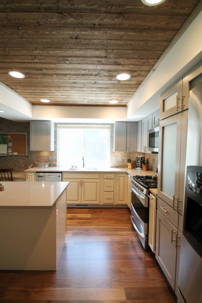 Inspiration for a large transitional l-shaped medium tone wood floor eat-in kitchen remodel in Denver with an undermount sink, shaker cabinets, gray cabinets, quartz countertops, gray backsplash, stone tile backsplash, stainless steel appliances and an island