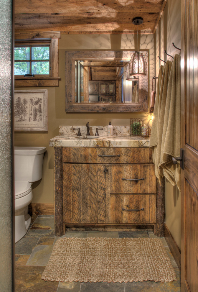 Photo of a mid-sized country master bathroom in Minneapolis with flat-panel cabinets, distressed cabinets, a two-piece toilet, beige walls, slate floors, an undermount sink, granite benchtops, multi-coloured floor and multi-coloured benchtops.