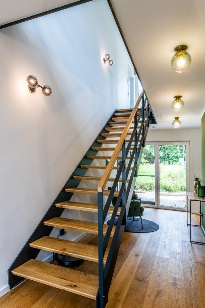 This is an example of a contemporary wood straight staircase in Nuremberg with open risers and metal railing.