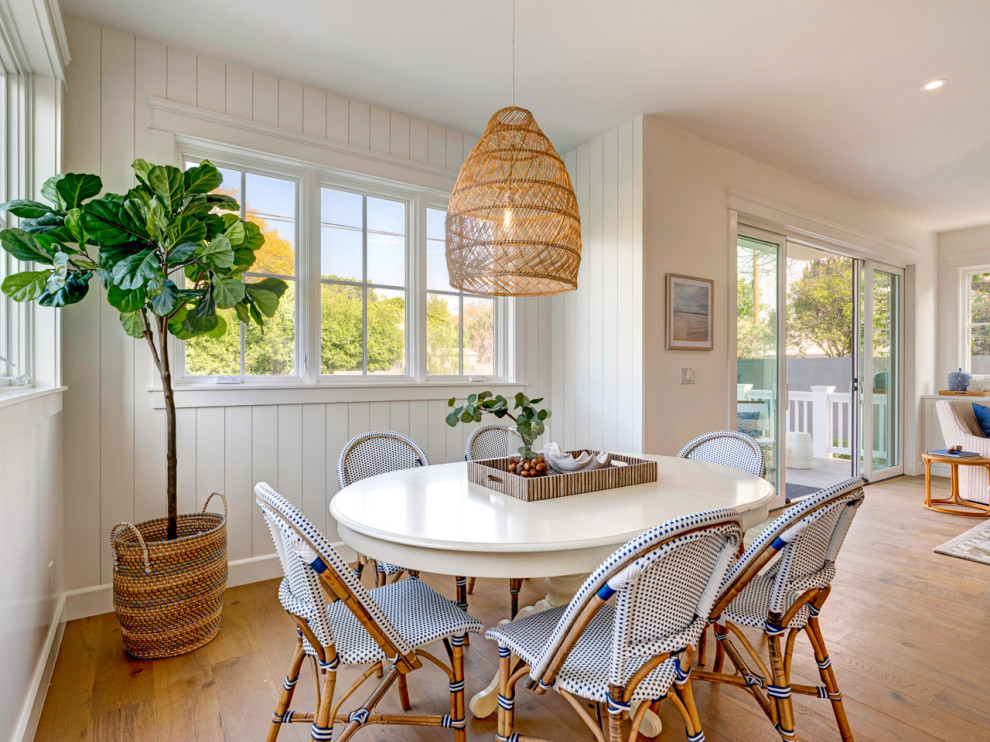 This is an example of a beach style open plan dining in Los Angeles with white walls, medium hardwood floors, brown floor and planked wall panelling.