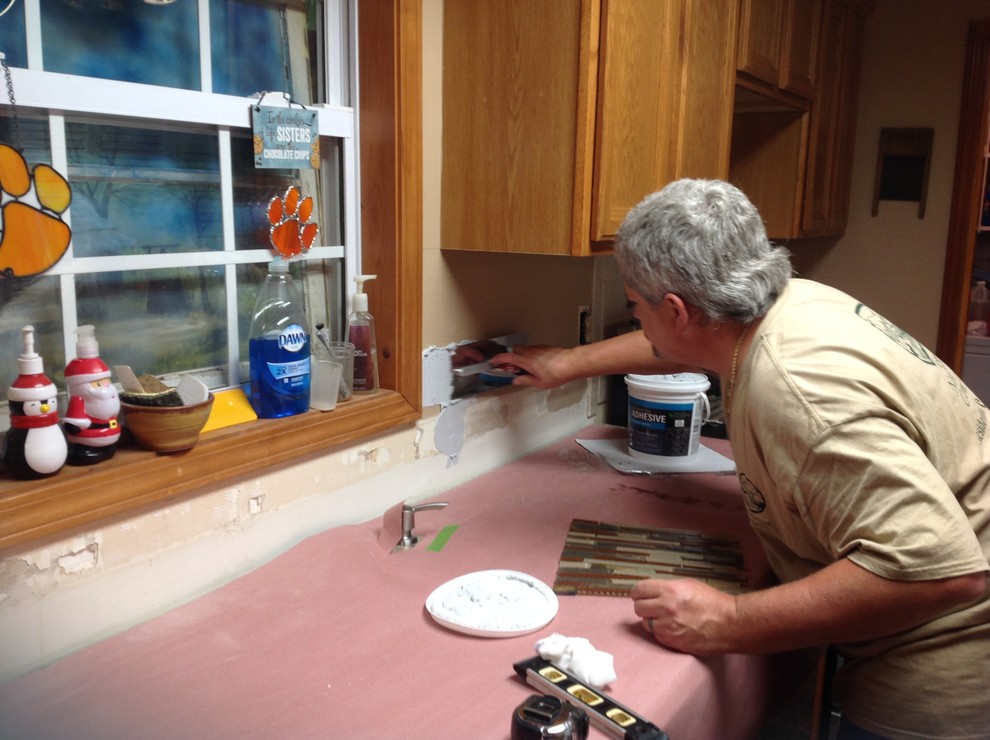 Inspiration for a l-shaped eat-in kitchen remodel with an undermount sink, flat-panel cabinets, brown backsplash, glass tile backsplash, stainless steel appliances and a peninsula