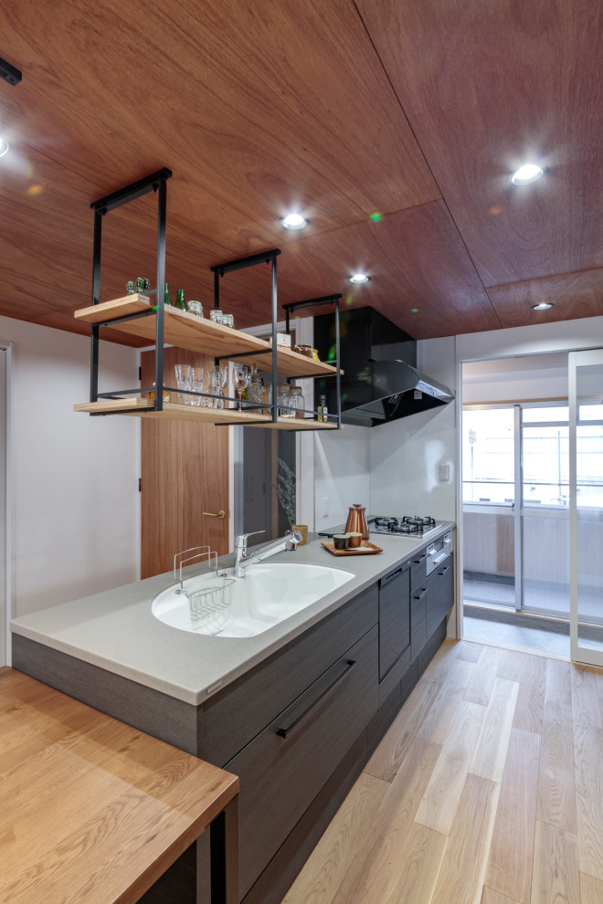 Inspiration for a midcentury single-wall open plan kitchen in Other with an integrated sink, grey cabinets, solid surface benchtops, white splashback, stainless steel appliances, light hardwood floors, beige floor, grey benchtop and timber.