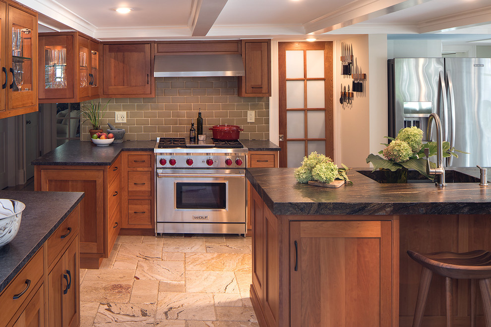 Photo of a large transitional u-shaped eat-in kitchen in New York with an undermount sink, shaker cabinets, medium wood cabinets, beige splashback, subway tile splashback, stainless steel appliances, with island, beige floor and limestone floors.