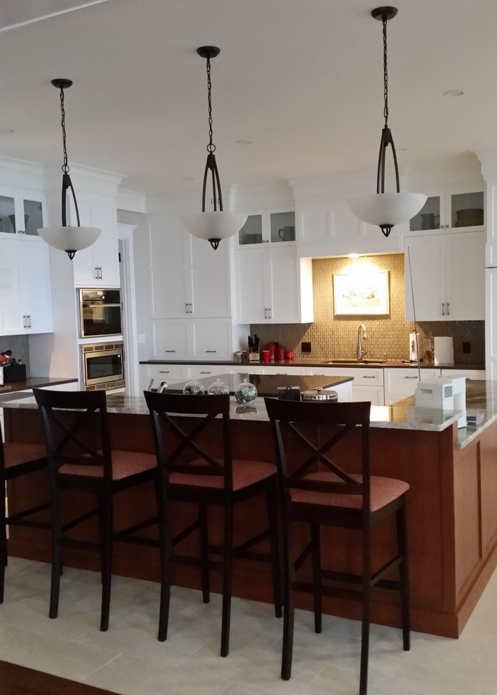 Example of a transitional ceramic tile eat-in kitchen design in Boston with a double-bowl sink, recessed-panel cabinets, white cabinets, quartz countertops, brown backsplash, glass tile backsplash, stainless steel appliances and an island