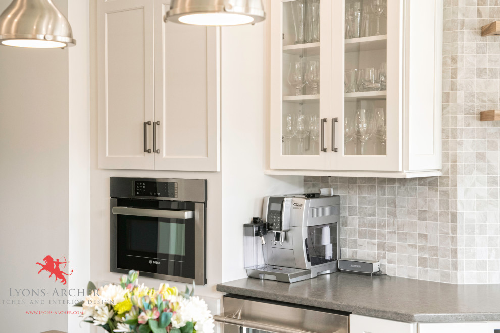 Eat-in kitchen - mid-sized transitional l-shaped medium tone wood floor and brown floor eat-in kitchen idea in Philadelphia with an undermount sink, shaker cabinets, white cabinets, quartz countertops, beige backsplash, mosaic tile backsplash, stainless steel appliances, an island and gray countertops