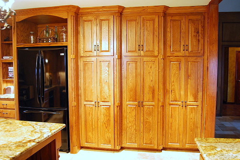 Example of a mid-sized mountain style u-shaped ceramic tile eat-in kitchen design in Dallas with a double-bowl sink, raised-panel cabinets, medium tone wood cabinets, granite countertops, beige backsplash, stone tile backsplash, black appliances and an island