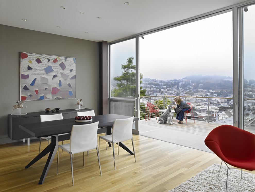 This is an example of a modern dining room in San Francisco with grey walls and light hardwood floors.