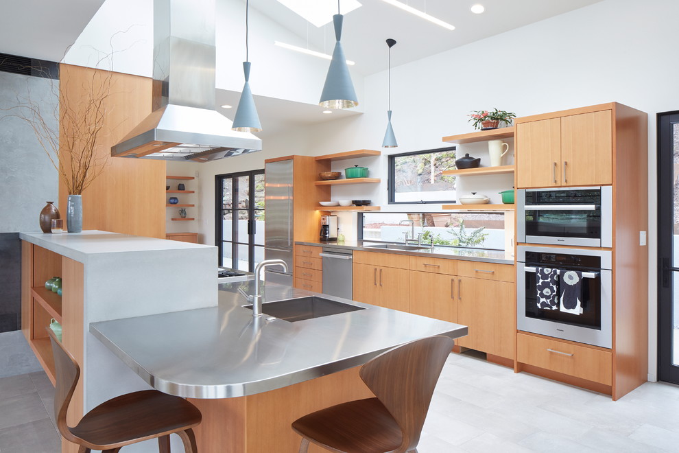 Design ideas for a mid-sized contemporary u-shaped kitchen in Portland with an undermount sink, flat-panel cabinets, medium wood cabinets, stainless steel benchtops, window splashback, stainless steel appliances, a peninsula, grey floor and grey benchtop.