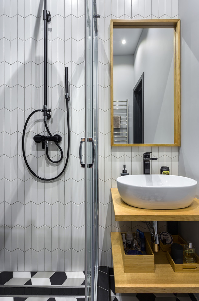 Inspiration for a small scandinavian 3/4 bathroom in Moscow with open cabinets, light wood cabinets, a corner shower, a wall-mount toilet, ceramic tile, ceramic floors, a drop-in sink, wood benchtops, multi-coloured floor, a sliding shower screen, white tile and black tile.