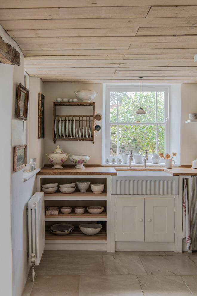 Inspiration for a small shabby-chic style single-wall kitchen/diner in London with a belfast sink, shaker cabinets, white cabinets, wood worktops, white appliances, no island, beige floors, brown worktops and a timber clad ceiling.