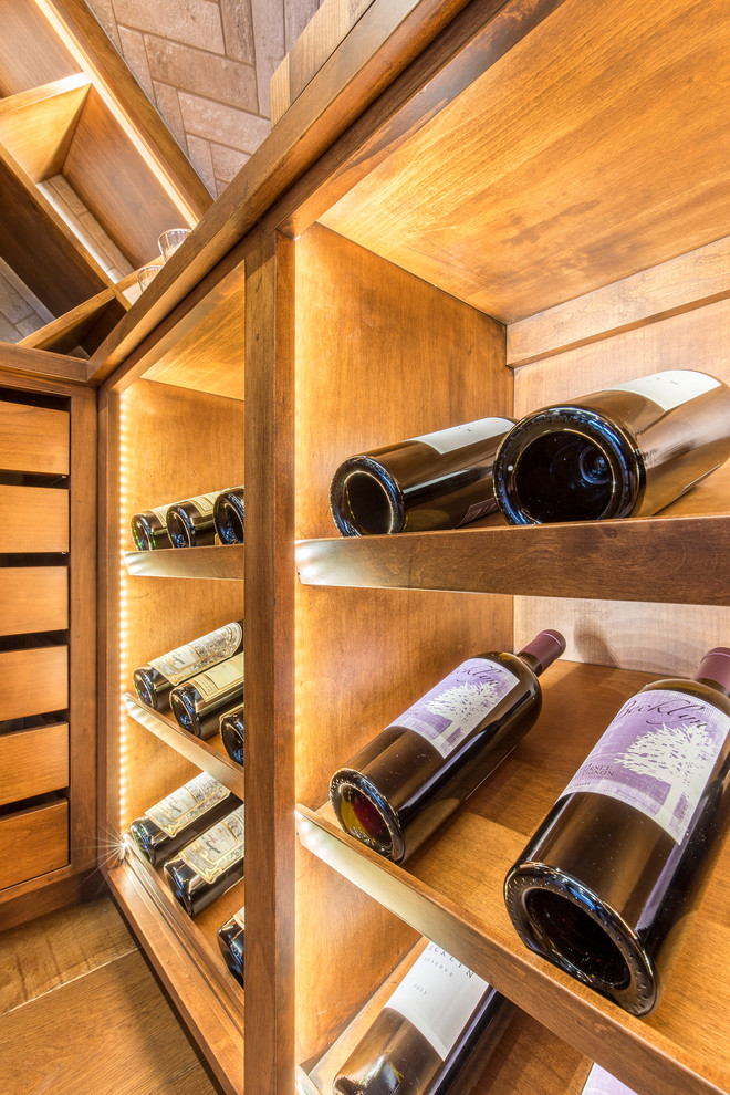 Photo of a mid-sized wine cellar in Austin with medium hardwood floors, storage racks and brown floor.
