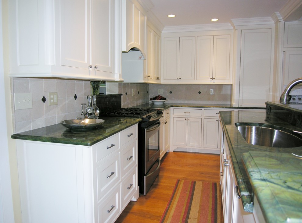 This is an example of a traditional l-shaped eat-in kitchen in Boston with an undermount sink, recessed-panel cabinets, white cabinets, granite benchtops, white splashback, stone tile splashback and stainless steel appliances.