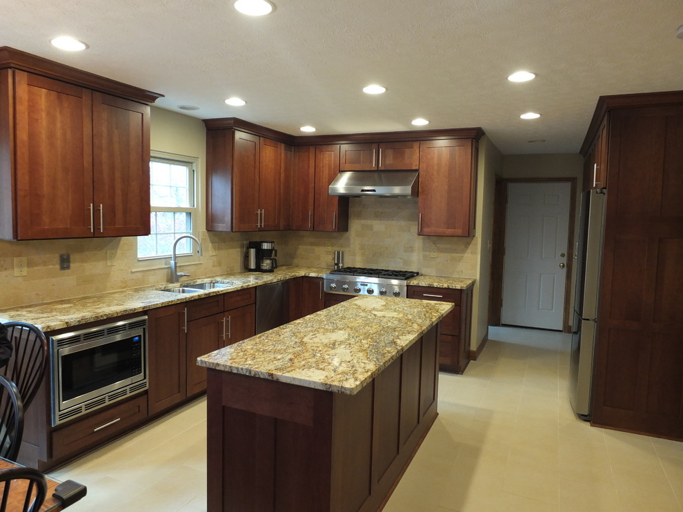 Example of a mid-sized transitional l-shaped ceramic tile eat-in kitchen design in Columbus with an undermount sink, shaker cabinets, brown cabinets, granite countertops, beige backsplash, ceramic backsplash, stainless steel appliances and an island