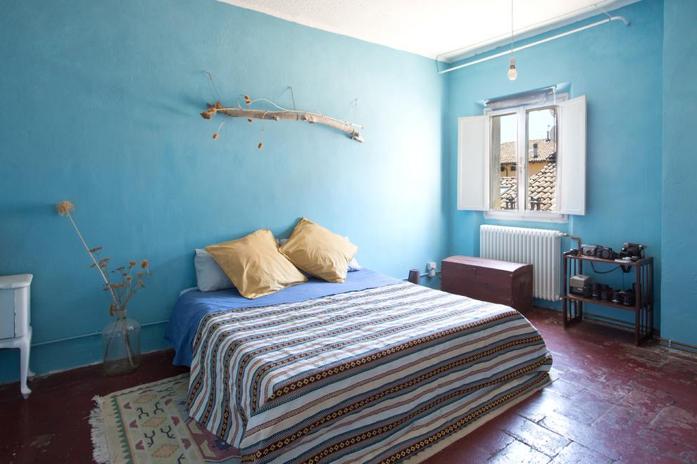Photo of a mediterranean master bedroom in Other with blue walls, terra-cotta floors and red floor.
