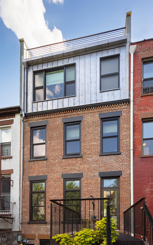 Photo of a modern three-storey grey townhouse exterior in New York with metal siding and a flat roof.