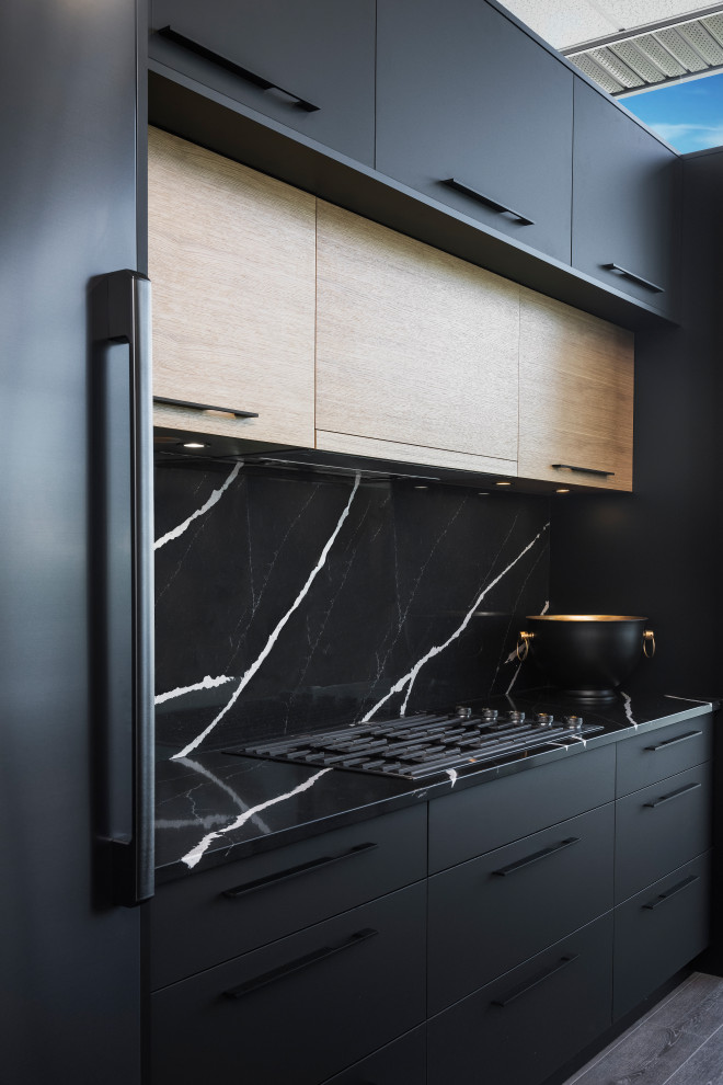 Modern kitchen in Vancouver with flat-panel cabinets, black cabinets, quartz benchtops, black splashback, engineered quartz splashback, black appliances, with island and black benchtop.