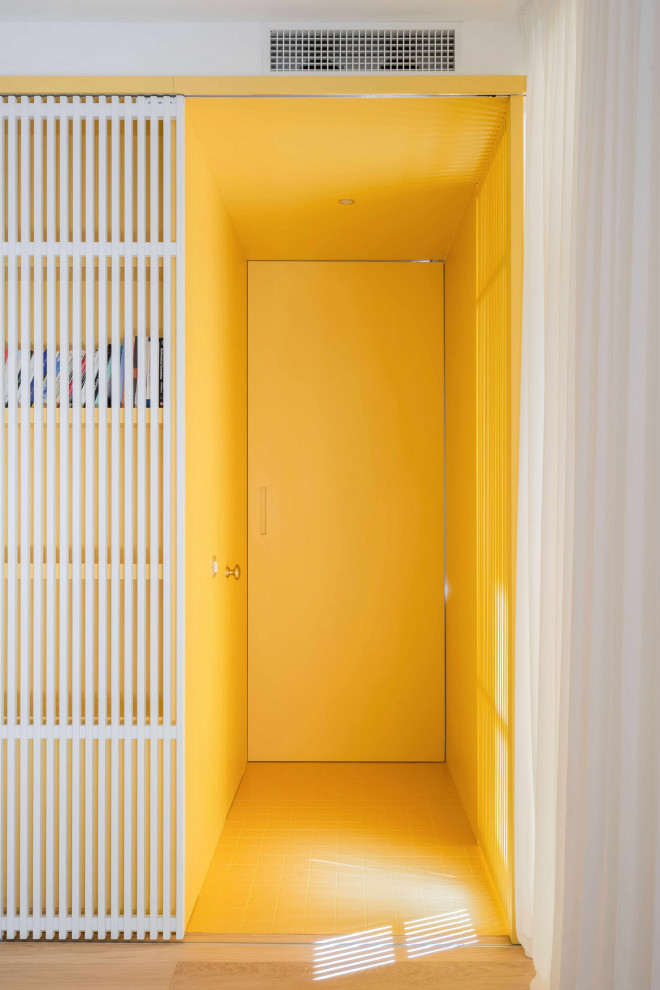 На фото: маленький коридор в современном стиле с желтыми стенами, полом из керамогранита, желтым полом, многоуровневым потолком и панелями на стенах для на участке и в саду