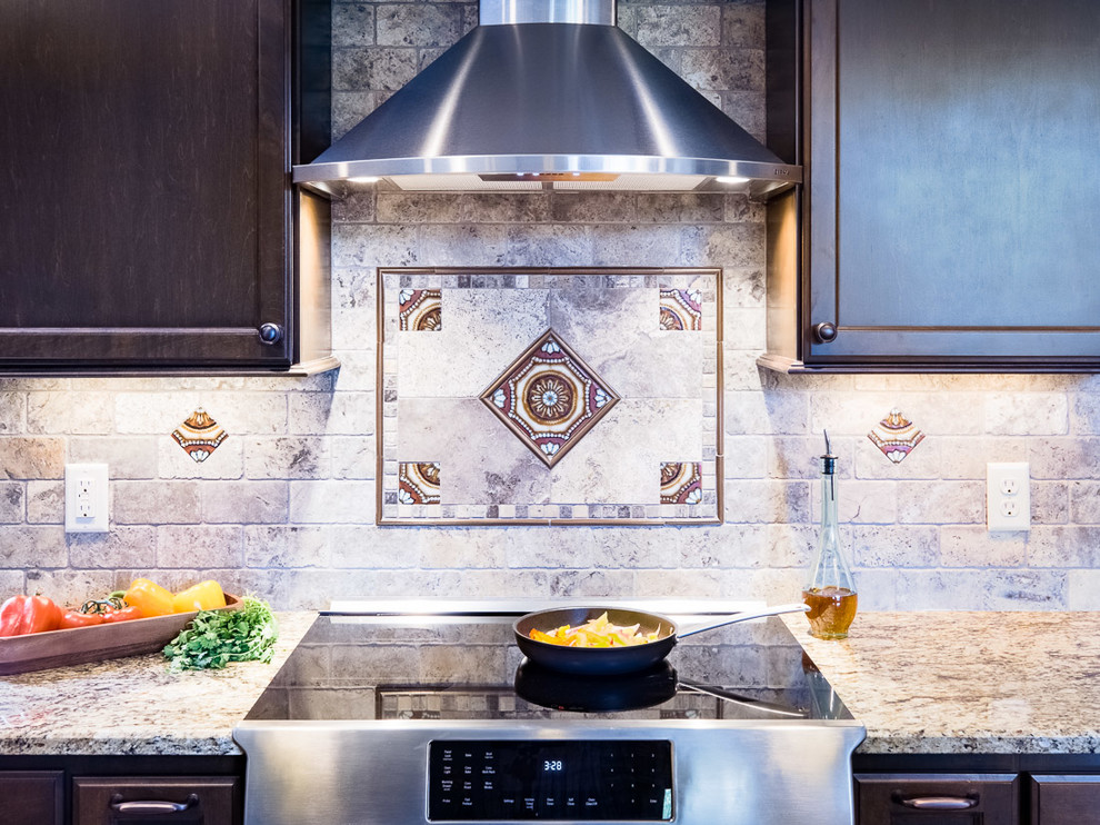Design ideas for a mid-sized mediterranean u-shaped eat-in kitchen in Minneapolis with a double-bowl sink, shaker cabinets, dark wood cabinets, granite benchtops, stone tile splashback, stainless steel appliances, medium hardwood floors and with island.