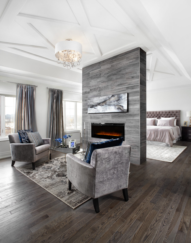 This is an example of an expansive transitional master bedroom in Toronto with white walls, dark hardwood floors and a ribbon fireplace.