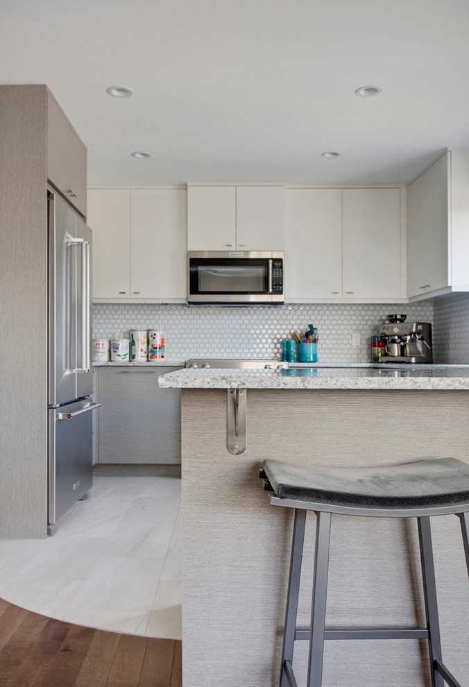 This is an example of a contemporary u-shaped kitchen in Calgary with an undermount sink, flat-panel cabinets, grey cabinets, granite benchtops, grey splashback, mosaic tile splashback, stainless steel appliances, porcelain floors and a peninsula.