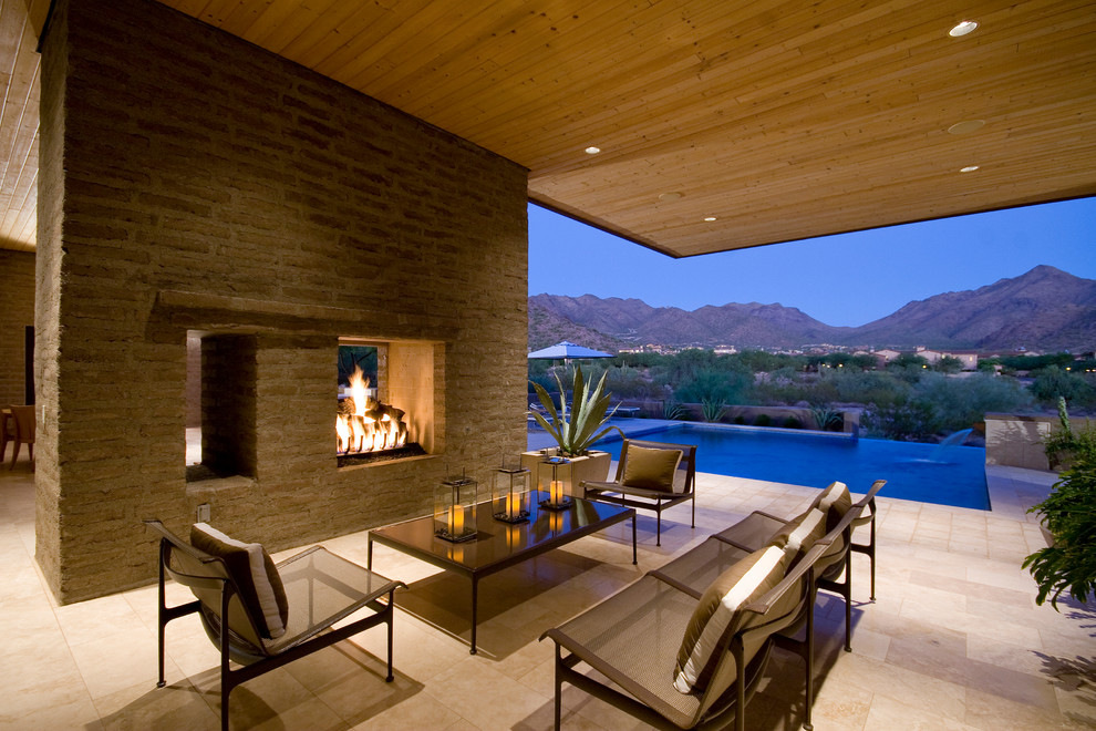 This is an example of a modern patio in Phoenix with a roof extension and with fireplace.