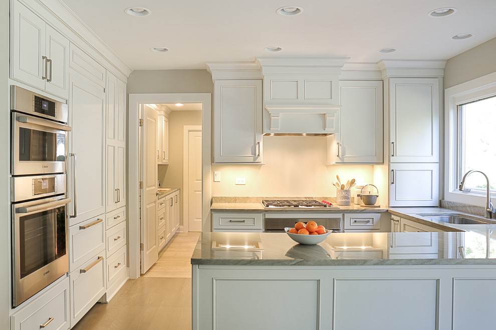 Photo of a small transitional galley eat-in kitchen in Chicago with an undermount sink, recessed-panel cabinets, white cabinets, quartzite benchtops, grey splashback, stone slab splashback, stainless steel appliances, light hardwood floors and a peninsula.