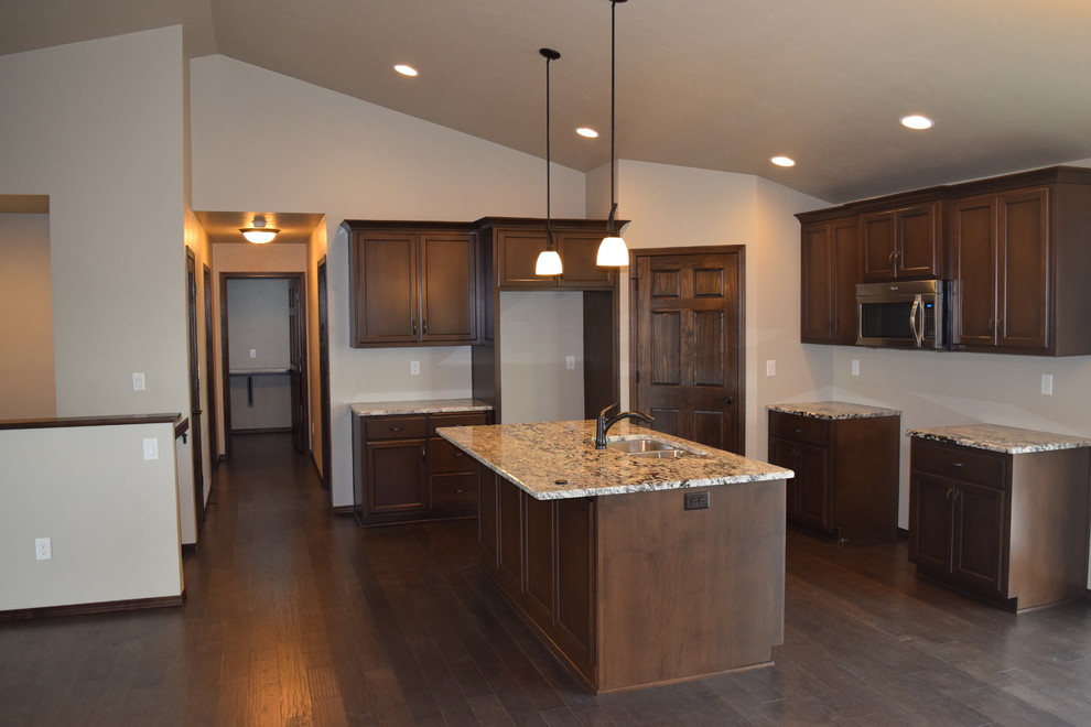 Example of a mountain style home design design with white cabinets, stainless steel appliances and an island