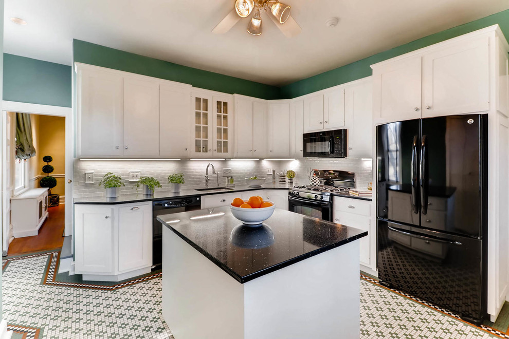 Photo of a beach style l-shaped separate kitchen in Baltimore with an undermount sink, shaker cabinets, white cabinets, white splashback, black appliances, with island and multi-coloured floor.