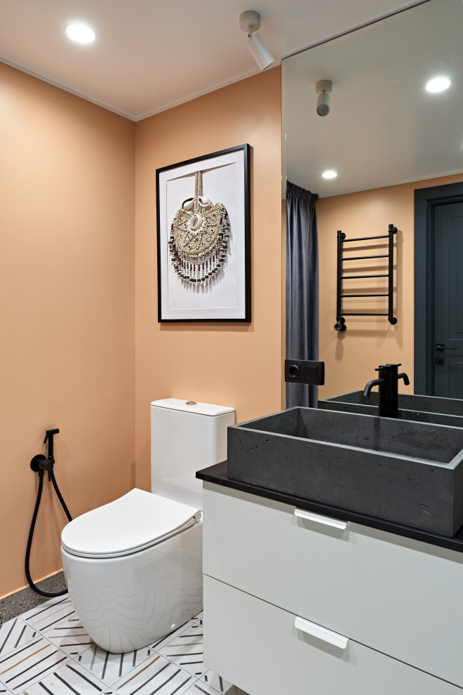 На фото: ванная комната среднего размера в скандинавском стиле с белыми фасадами, душем в нише, унитазом-моноблоком, коричневой плиткой, керамогранитной плиткой, оранжевыми стенами, полом из керамической плитки, накладной раковиной, столешницей из искусственного камня, разноцветным полом, шторкой для ванной, серой столешницей, тумбой под одну раковину и подвесной тумбой с