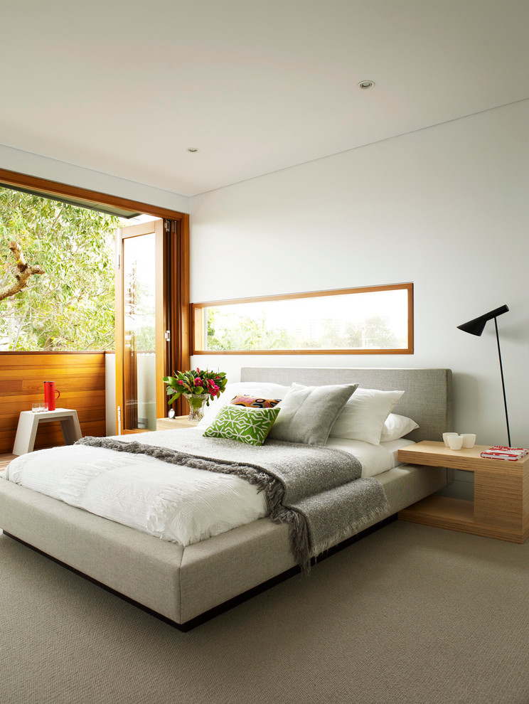 Mid-sized modern bedroom in Sydney with white walls and carpet.