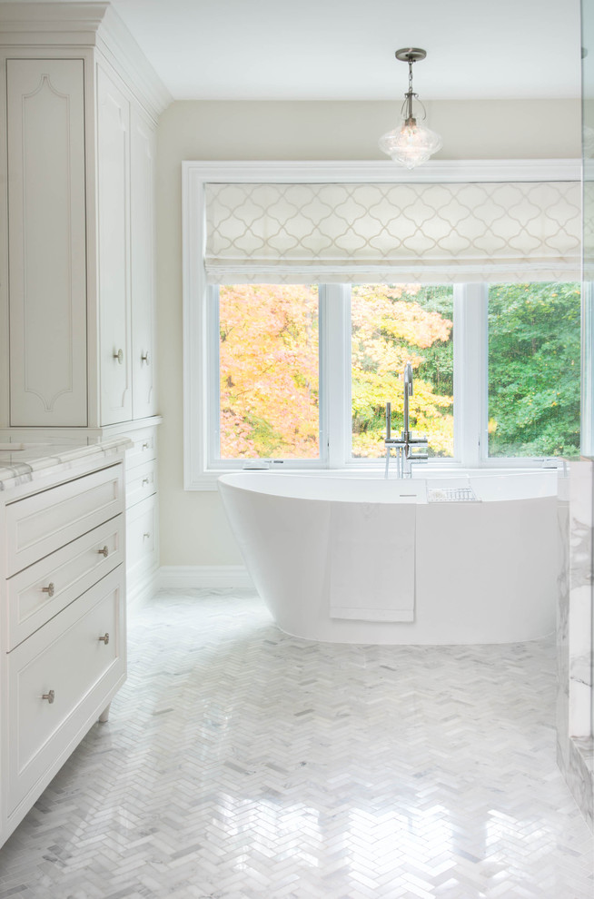 Inspiration for a large transitional master bathroom in Toronto with an undermount sink, beaded inset cabinets, white cabinets, marble benchtops, a freestanding tub, a corner shower, a one-piece toilet, white tile, stone tile, white walls, marble floors, white floor and a hinged shower door.