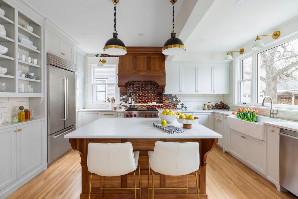 Inspiration for a large transitional u-shaped light wood floor and beige floor eat-in kitchen remodel in Minneapolis with a farmhouse sink, recessed-panel cabinets, blue cabinets, quartz countertops, multicolored backsplash, ceramic backsplash, stainless steel appliances, an island and white countertops