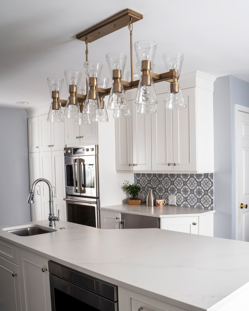 Inspiration for a mid-sized transitional l-shaped medium tone wood floor and brown floor eat-in kitchen remodel in St Louis with a farmhouse sink, recessed-panel cabinets, white cabinets, quartz countertops, blue backsplash, ceramic backsplash, stainless steel appliances, an island and white countertops