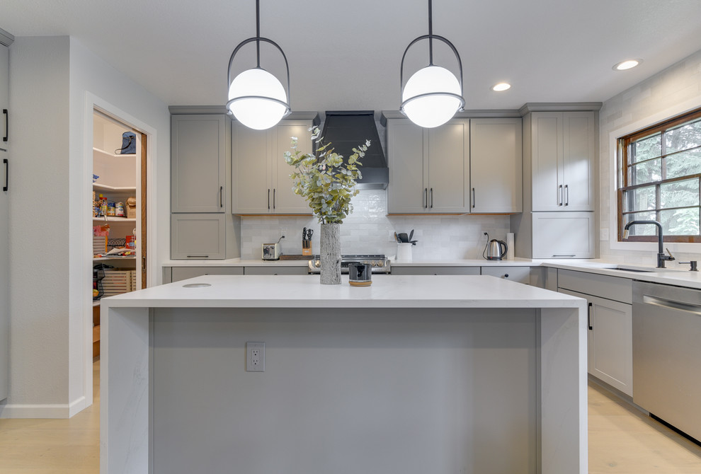 Mid-sized transitional u-shaped open plan kitchen in Portland with an undermount sink, shaker cabinets, grey cabinets, quartzite benchtops, grey splashback, ceramic splashback, stainless steel appliances, light hardwood floors, with island, beige floor and white benchtop.