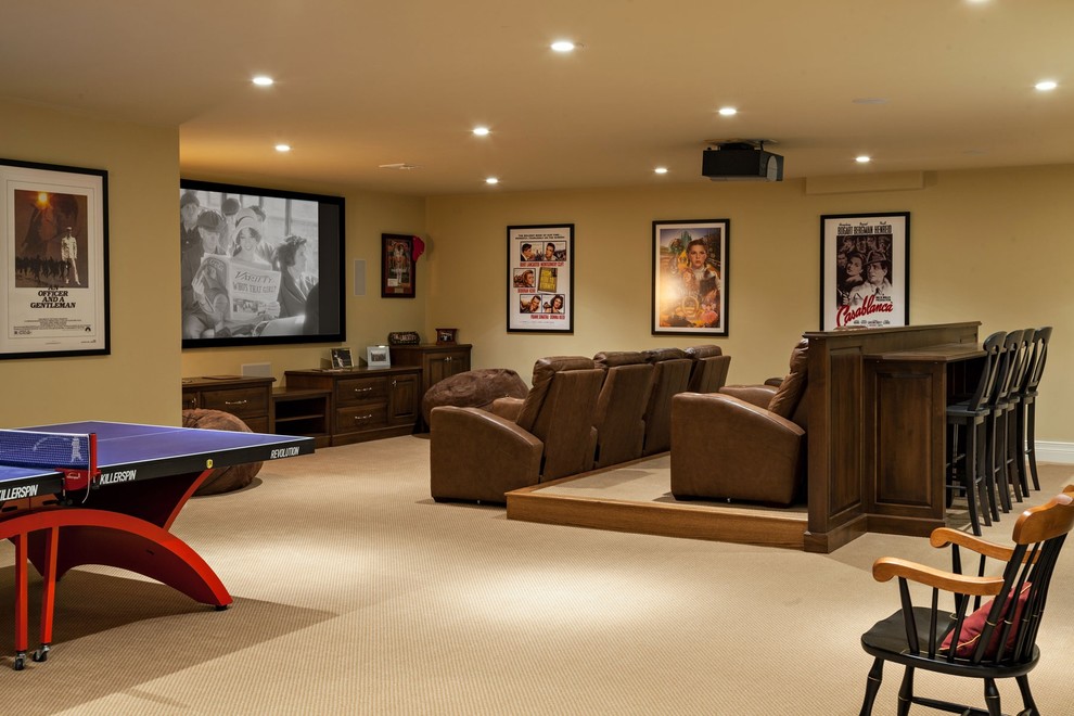 This is an example of a large beach style open concept home theatre in Boston with beige walls, carpet and a projector screen.