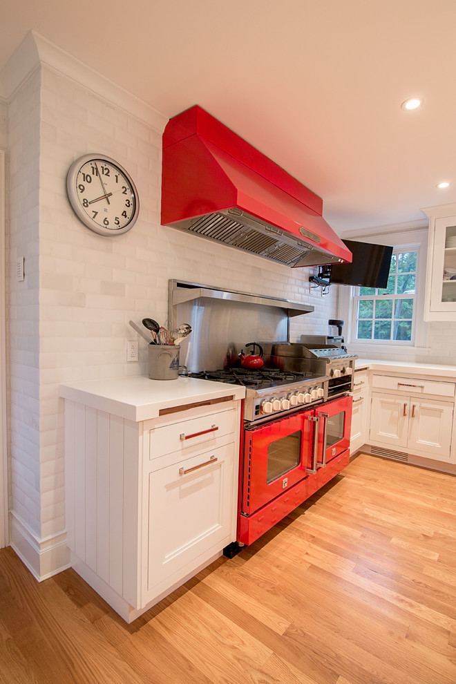 Photo of a transitional u-shaped eat-in kitchen in New York with shaker cabinets, white cabinets, white splashback, subway tile splashback and coloured appliances.