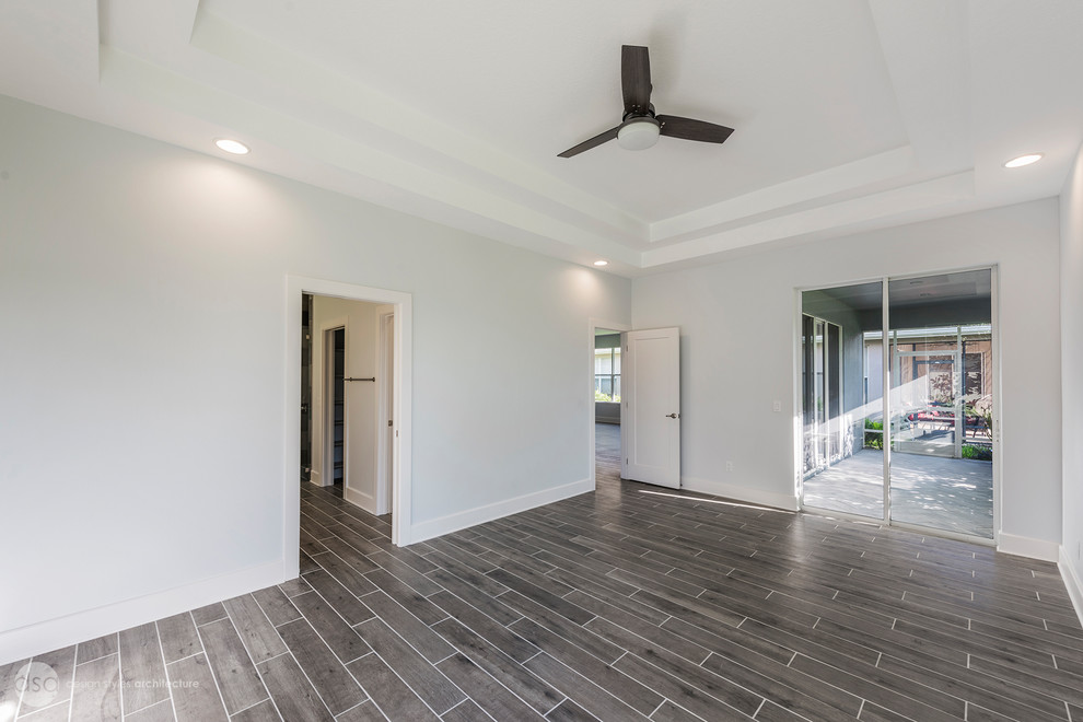 This is an example of a large transitional master bedroom in Tampa with blue walls, porcelain floors and grey floor.