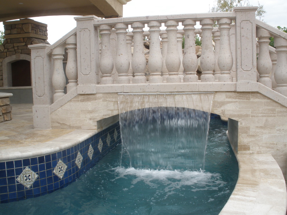 Large mediterranean backyard custom-shaped pool in Phoenix with a water slide and tile.